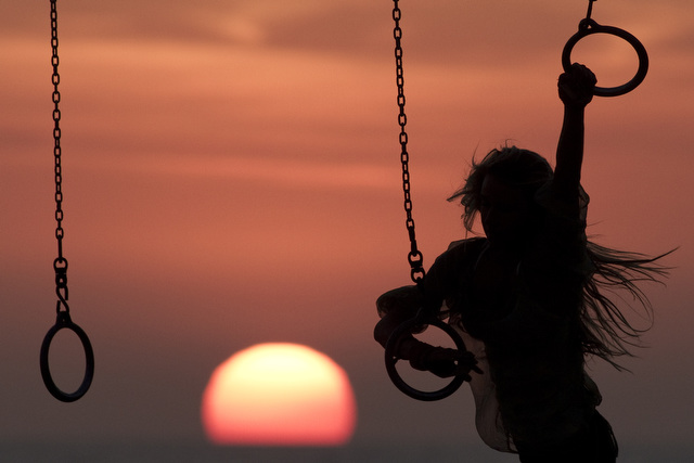 Kara Sadlik works out on the rings as the sun sets at the original "Muscle Beach" workout area in Santa Monica, California